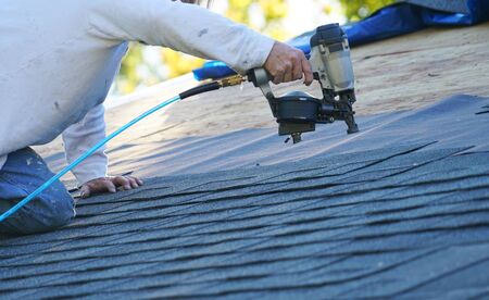 Roofing Installation Residential roofing contractor installing asphalt shingles using nail gun